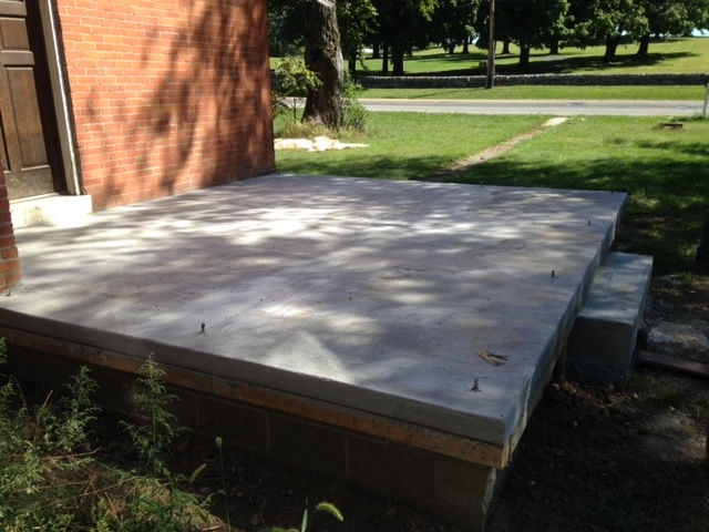 A brick building with a concrete platform in front of it