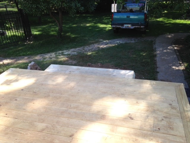 A blue truck is parked next to a wooden deck