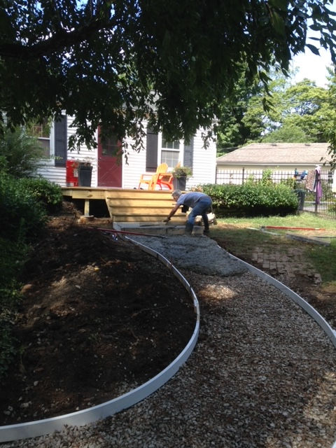 A man is working on a walkway in front of a house