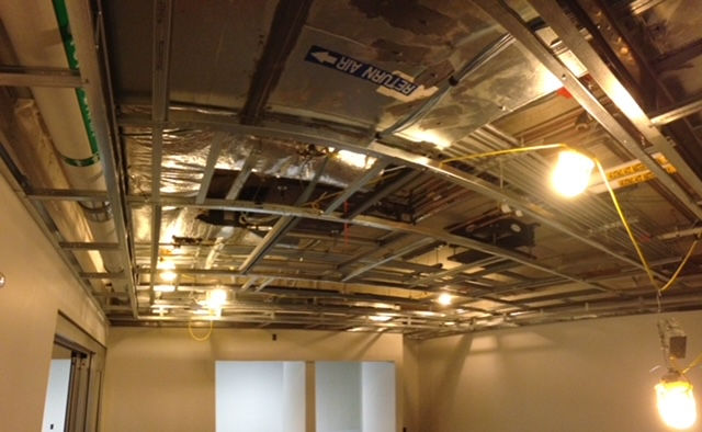 A room with a ceiling that is being built and a light hanging from the ceiling.