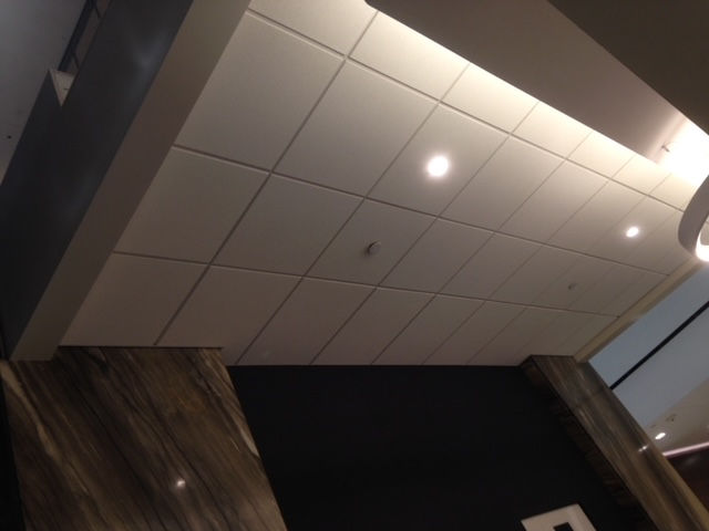 A white tiled ceiling in a room with a black wall