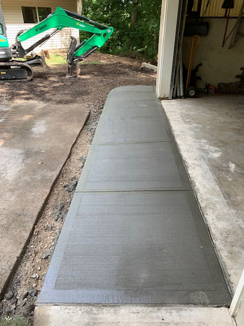 A concrete walkway is being built next to a garage.