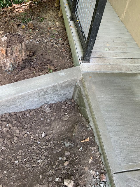A concrete walkway is being built next to a fence.