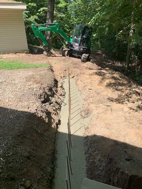 A green excavator is digging a trench in the dirt.
