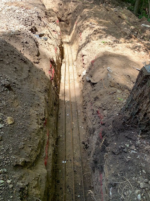A trench in the ground with a tree stump in the middle of it.