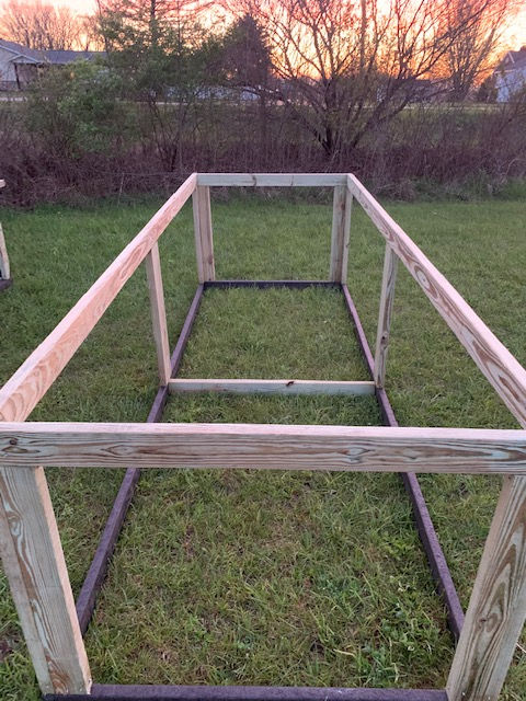 A wooden frame is sitting on top of a lush green field.