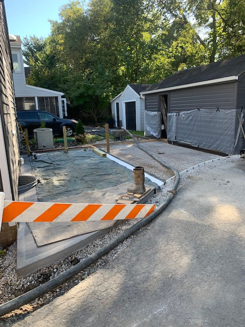 A concrete driveway is being built in front of a house.