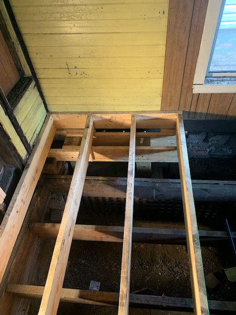 A wooden floor is being built in a room with a yellow wall.