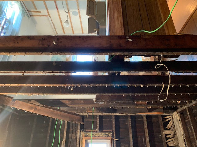 A room with wooden beams and wires hanging from the ceiling.