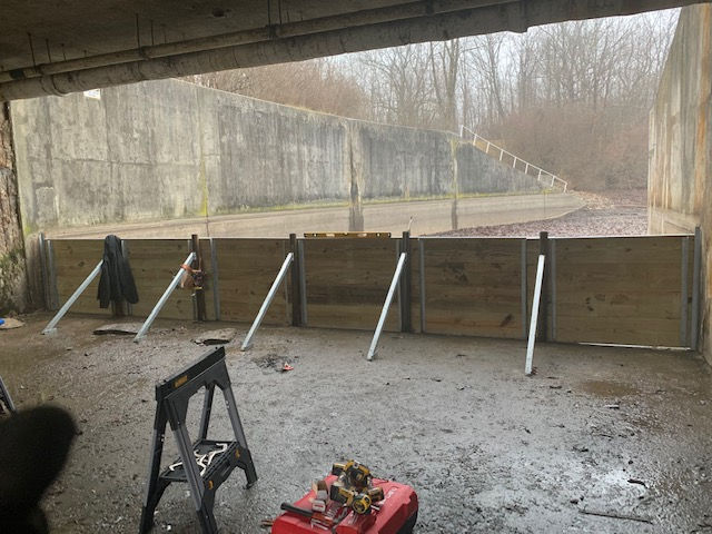 A wooden fence is being built under a bridge.