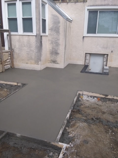 A concrete walkway is being built in front of a house