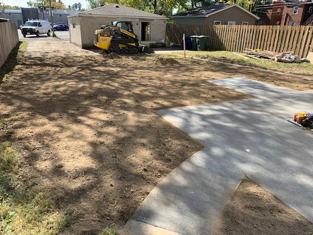 A yellow bulldozer is sitting in the dirt in front of a house.