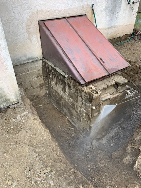 A brick building with a red roof and a hole in the ground.