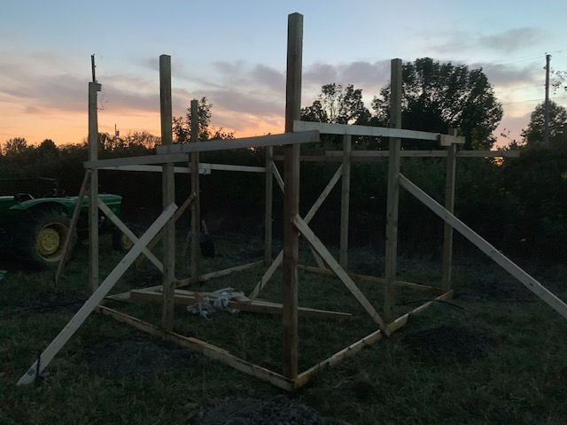 A john deere tractor is parked behind a wooden structure
