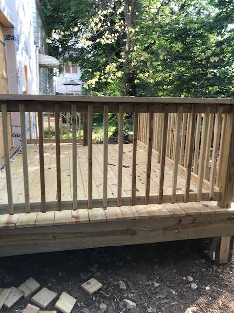 A wooden deck with a railing in the backyard