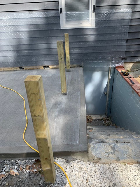 A wooden railing is being built on the side of a house.