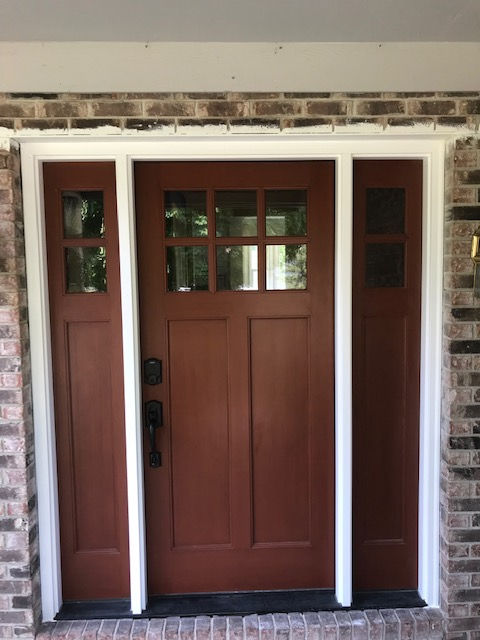 A brown door with a white trim is on a brick wall.