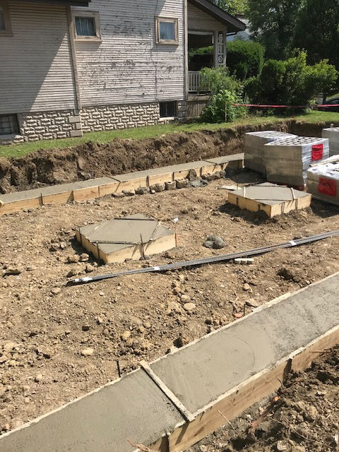 A concrete walkway is being built in front of a house.