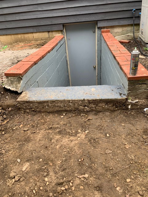 A basement door is being built into the side of a house.