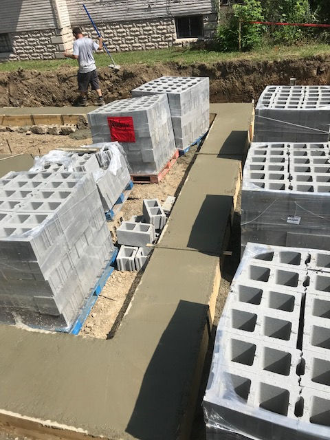 A man is standing next to a pile of concrete blocks.