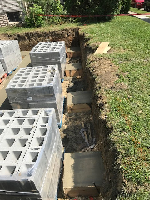 A row of concrete blocks are sitting in a trench in the grass.