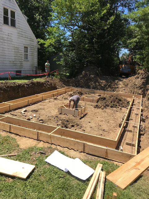 A man is working on a construction site in front of a house