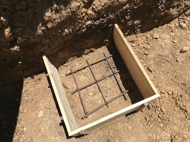 A wooden box is sitting in the dirt next to a metal grid