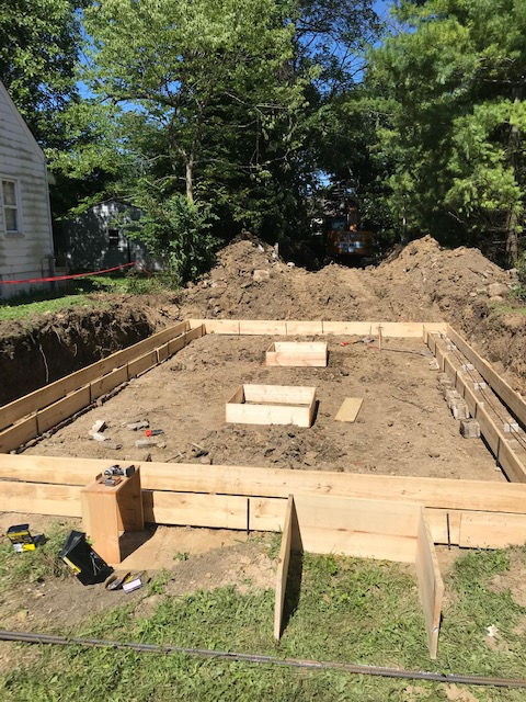 A wooden foundation is being built in the backyard of a house.