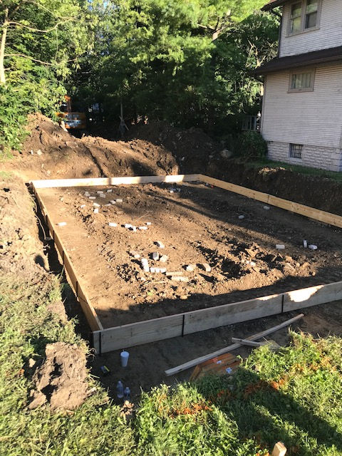 A concrete foundation is being built in front of a house