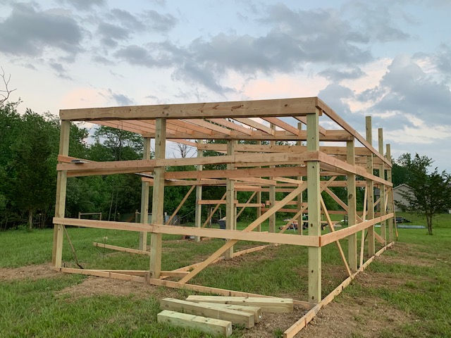 A large wooden structure is being built in a grassy field.