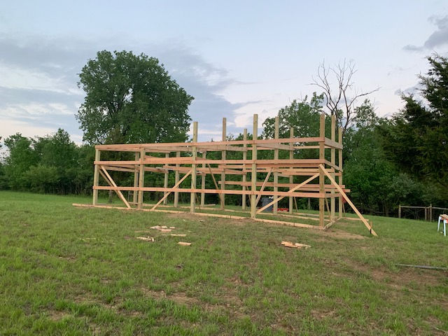 A wooden structure is being built in a grassy field.