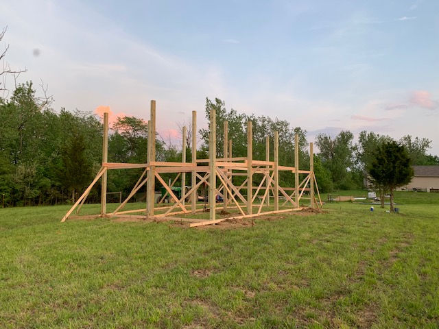 A large wooden structure is being built in a grassy field.
