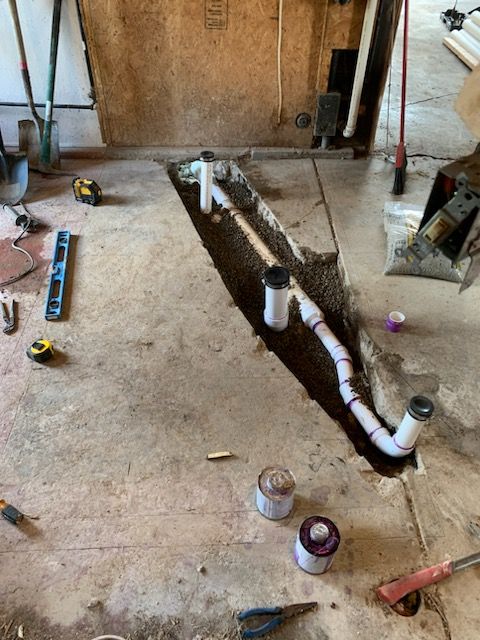 A drain pipe is being installed in a hole in the floor.