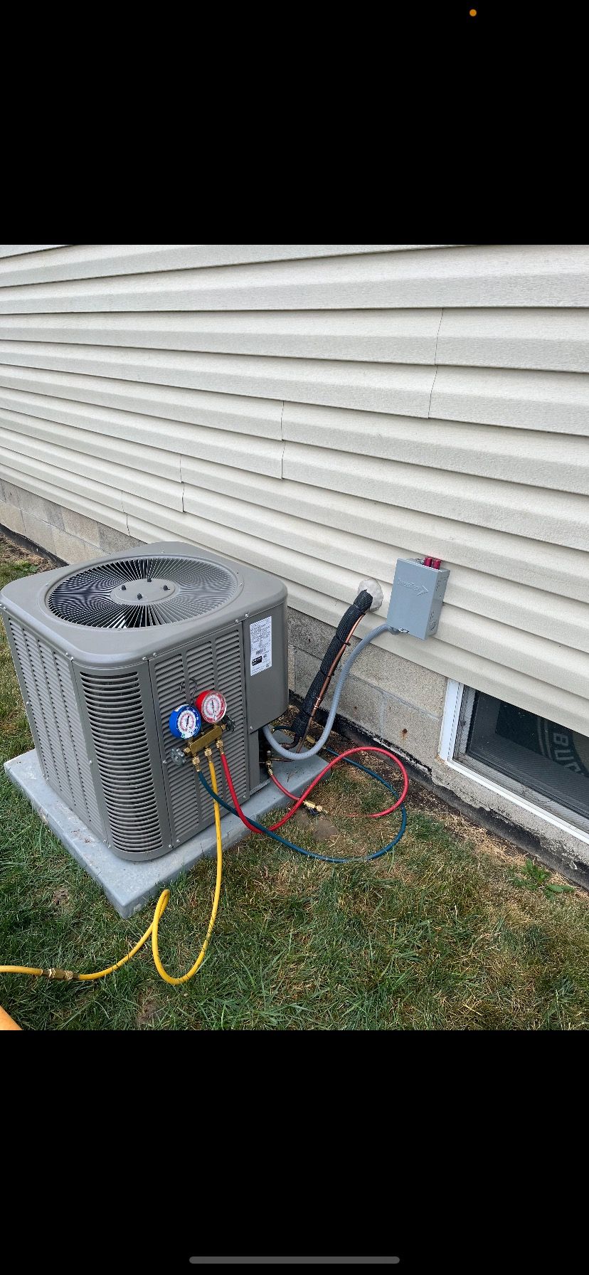 An air conditioner is being installed on the side of a house.