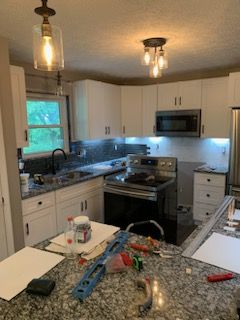A kitchen with white cabinets and granite counter tops is being remodeled.
