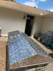 A stainless steel grill is sitting in front of a house.
