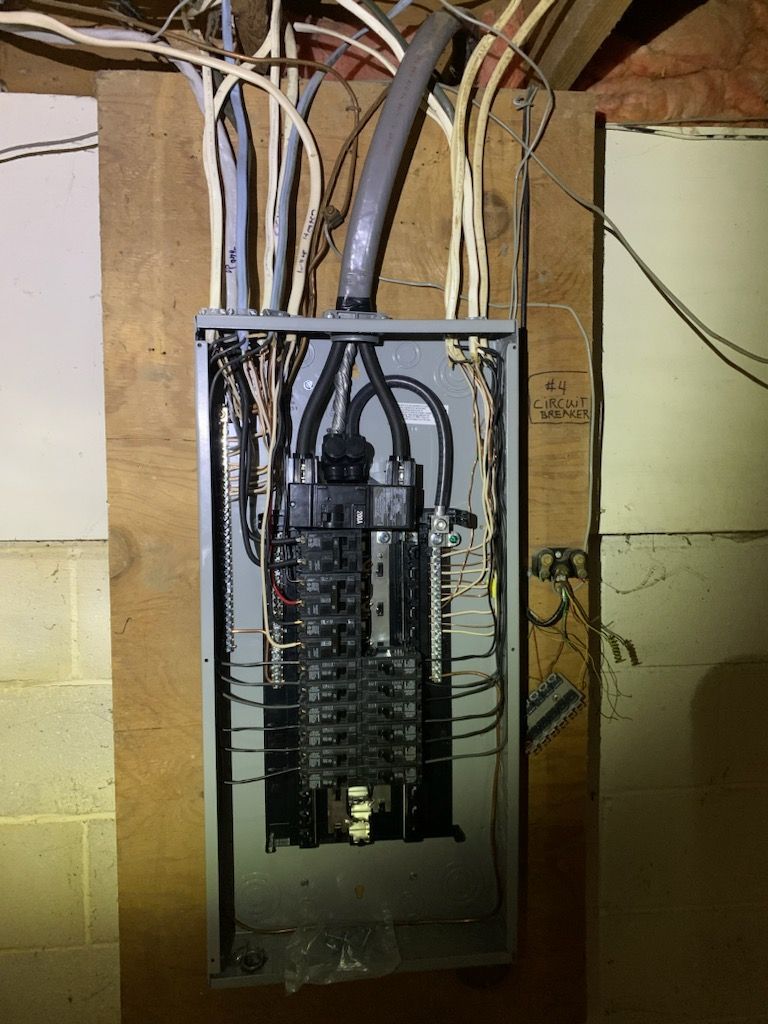 An electrical box is hanging on a wooden wall.