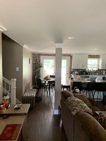 A living room with a couch , table and chairs and a kitchen.