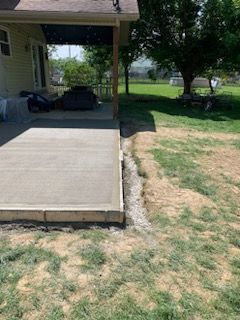 A concrete patio is being built in the backyard of a house.