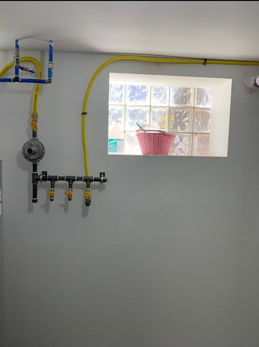 A room with a window and a bunch of pipes hanging from the ceiling.