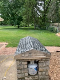 A propane tank is sitting inside of a stone structure.
