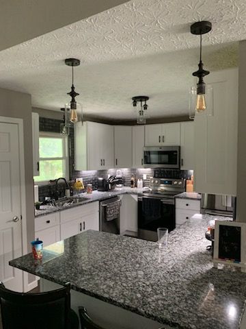 A kitchen with granite counter tops , white cabinets , stainless steel appliances