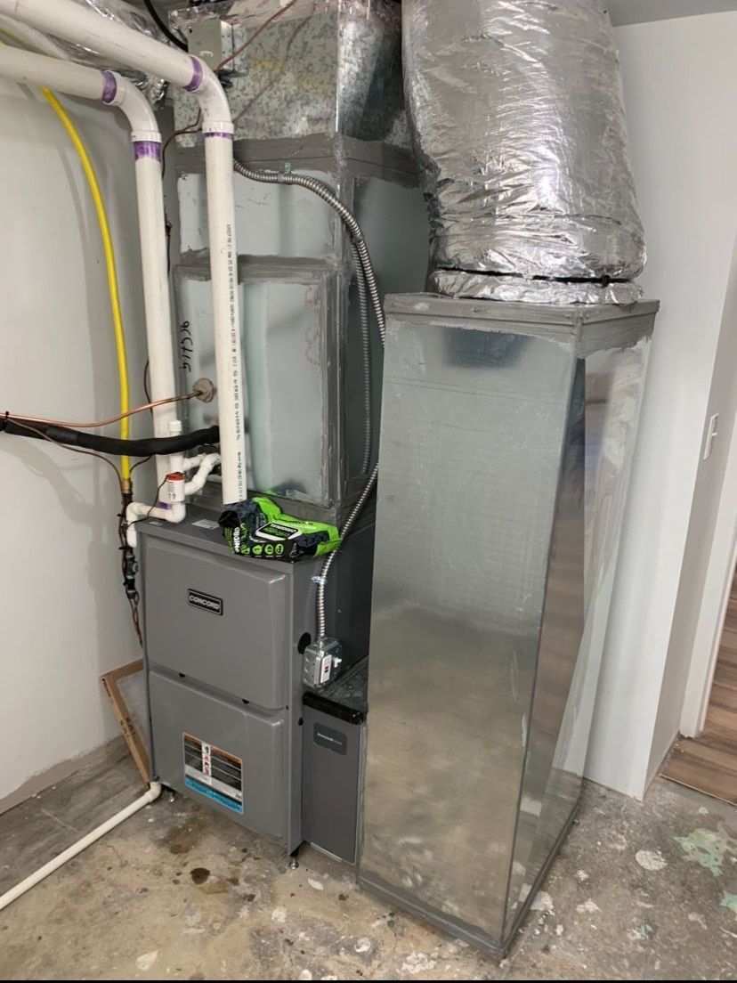 A furnace is sitting in a basement next to a pipe.