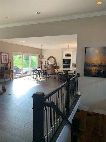 A living room with a black railing and a painting on the wall.