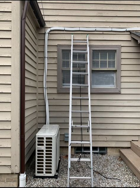 A ladder is sitting on the side of a house next to a window.