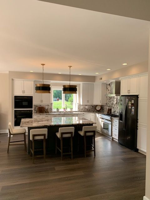 A kitchen with white cabinets and a black refrigerator