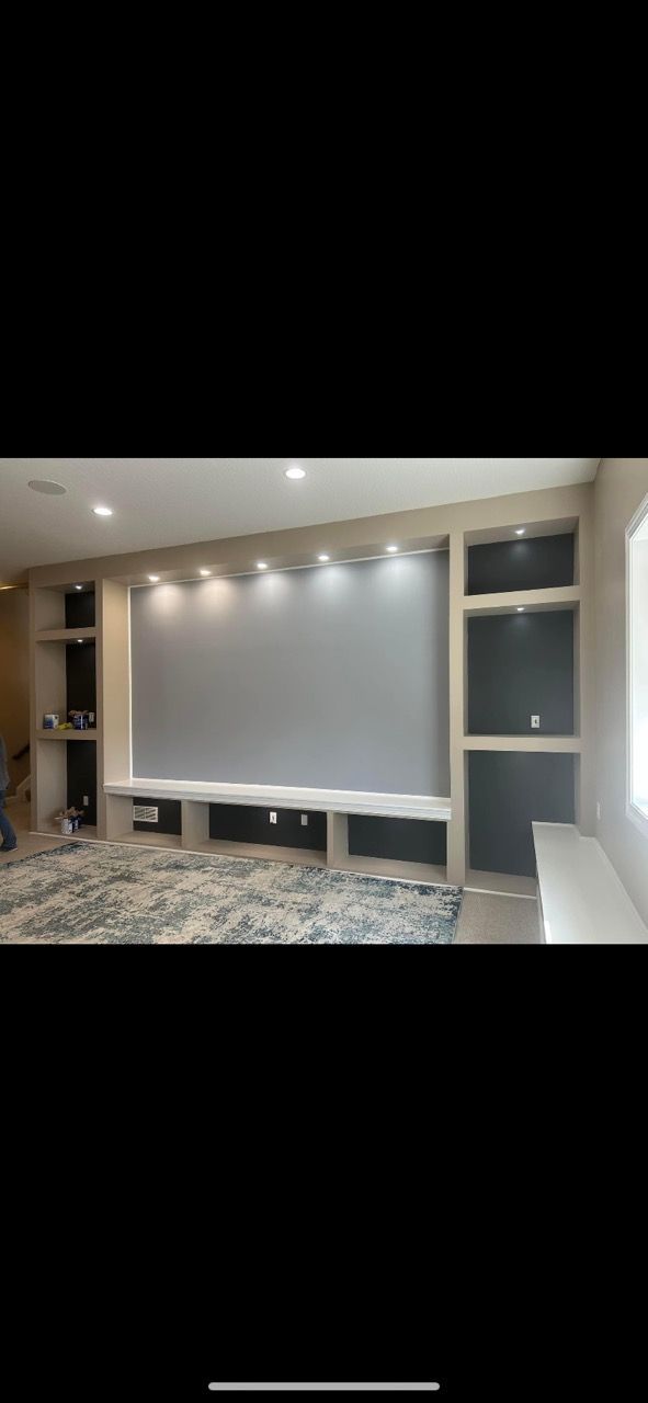 A living room with a large screen on the wall.