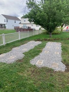 A yard with a white fence and a tree in the background.