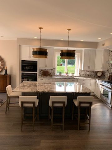 A kitchen with a large island and stools in it.
