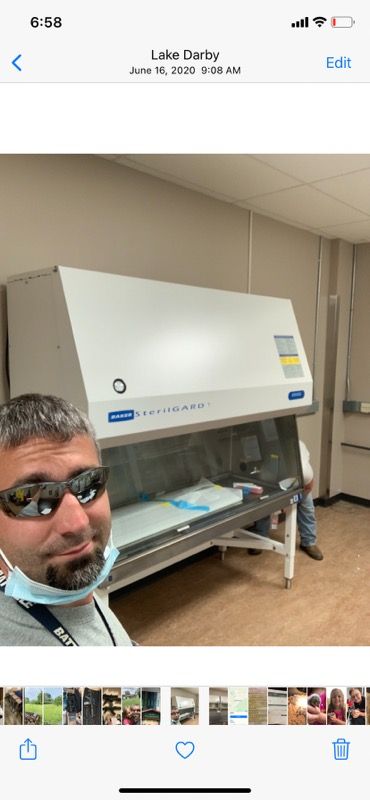 A man wearing sunglasses and a mask is standing in front of a machine.